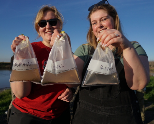 Researchers hold water sample bags from the river, canal, and floodplain, demonstrating the productivity of invertebrates in the floodplain.